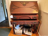 Front view of antique wooden secretary desk showing carved floral inlay on drop-front and two lower drawers with ornate metal handles.
