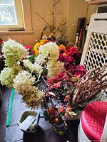 Wide view of assortment of faux flowers and dried hydrangea with baskets and arranging tools