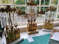 Front view showing all three brass and crystal girandoles against a window backdrop