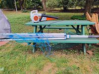 Metal drying rack horizontal view showing blue lines tangled and spread across rack legs on green grass near picnic table.