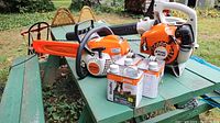 Overall view of BG50 blower, MS 181 C chainsaw and three fuel cans on green table