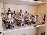 Front view of the four-piece Reed & Barton silver plated Winthrop tea set displayed on a shelf.