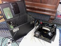 Open black hard carrying case with interior lining, includes foot pedal, power cord, and manual