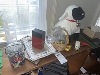 Photo of tabletop with marbles in glass container, pencil sharpener, picture frames, and plush lamb toy.