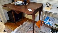 Front view of vintage wooden drop leaf table with contents on top removed.