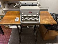 Vintage Royal manual typewriter on wooden rolling typewriter table with metal legs.