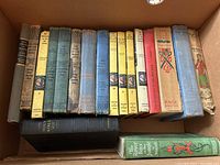 Box with 17 vintage hardcover books including Nancy Drew, The Hardy Boys, and others showing aged bindings and covers.