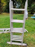 Front view of folded Werner extension ladder showing aluminum construction and stepped rungs with some weather marks.