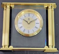 Birks quartz clock with gold-tone pillars and round clock face with Roman numerals under glass frame.