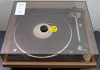Dual CS 502-1 turntable with dust cover closed, showing wood grain base and yellow adapter on platter.