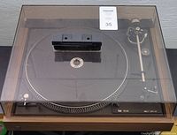 Dual CS 506-1 turntable with closed clear dust cover, shows wooden base and platter with record holder clamp on top.