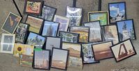 First photo showing all 27 framed art photos and prints laid out on the floor with various subjects and mostly gold frames.