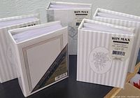 Seven white WIN MAX photo albums with decorative and striped covers, indicated on label for 100 4x6 photos capacity.