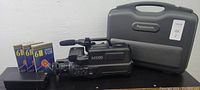 Panasonic M1000 VHS movie camera alongside three blank VHS-C tapes in boxes and a Panasonic hard case