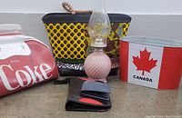 Photo showing the Coca-Cola bag, Canada bucket, men's wallet, oil lamp, and women's purse with assorted items
