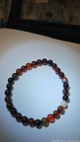 Full view of natural dream agate stretchy bracelet with round polished beads in mixed earthy colors.