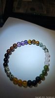Photo of the natural mixed gemstone bracelet with 6mm beads arranged in a circle under bright light, showing various stone colors and textures.