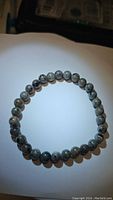Photo of the natural yooperlite bracelet laid flat showing the round gray beads with speckled patterns.