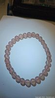 Photo of natural pink strawberry quartz round bead stretchy bracelet laid flat showing bead shape and color