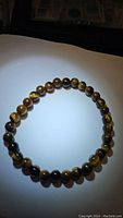 Yellow tigerseye stretchy bracelet laid flat in a circular shape, showing polished beads and tigerseye pattern
