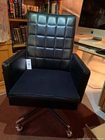 Front angle showing black leatherette with quilted pattern backrest, cloth seat, armrests, and chrome base with casters.
