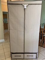 Front view of beige collapsible clothes wardrobe with two zippered drawers at bottom and vertical zipper door.