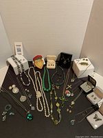 Overview of all jewelry items arranged on black surface with white props