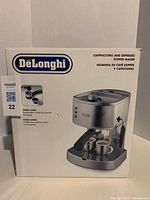 Front of box showing DeLonghi EC-330 espresso and cappuccino maker with crema filter and product photo.