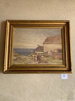 Framed watercolour print titled "The Old Capstan" hanging on a wall with visible gold-tone frame and coastal scene with boats and buildings.