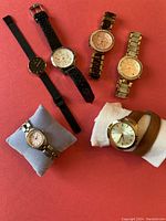 All six ladies watches laid out showing different strap styles and face designs against a red background.