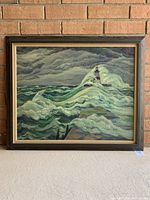 Full view of the framed oil painting showing the lighthouse and stormy sea