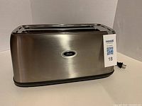 Side view of the 4-slice toaster showing stainless steel body and Oster logo on front.