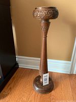 Full view of the teak wood ash tray stand on floor showing entire stand and base with floral carvings.