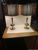 Pair of vintage brass lamps with cylindrical wood slat shades seen from front on a table.
