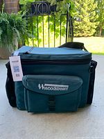 Closed green Woodstream fishing tackle bag showing front logo and strap