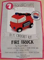 Close-up of the crochet kit packaging showing the fire truck image, kit title, brand and contents.