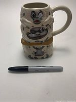 Stacked Disney character ceramic mugs with sharpie marker for scale