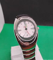 Front view of men's silver-tone quartz watch with white dial showing time and sub-dial detail on green background.