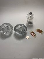Photo of two textured glass snowball candle holders, clear with crackled texture, a clear Peugeot pepper grinder, two wrapped Beatles hair pomade bars, and a coin for scale.