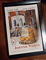 Vintage Johnnie Walker whisky advertisement print showing bottle, glasses, a man working on a gate, and a stately brick house in the background. Text and branding visible.