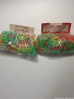 Two sealed bags with multiple small plastic sports toy figures in bright colors and paper labels sewn into the packaging, displayed on white background.