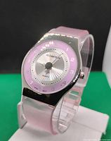 Front and angled view of a women's Asiantec quartz watch with a pink wristband, stainless steel metallic watch case, and silver/pink dial with Arabic numerals.