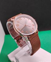 Side-angle view of the women's quartz wristwatch showing the round silver-tone dial with rose gold-tone numerals and brown fabric strap.