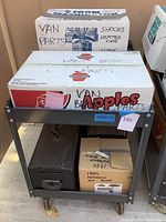 Metal cart holding boxes of van car parts and vintage radios.
