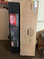 Coleman 6-person Instant Cabin tent in black carry bag and original cardboard box side by side