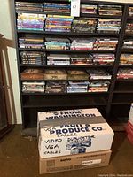 Tall shelving with many DVD cases, assorted movies and shows, along with boxes including Sanyo DVD VCR player box at the bottom.