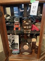 Front cabinet view showing truck model, ceramic mugs, vintage tins, piggy bank, motorcycle model, and photo