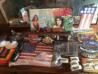 Photo showing multiple Harley Davidson patches, pins, American flag items, and two motorcycle magazines with women on the cover.