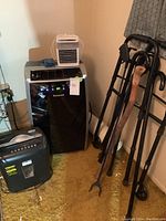 Overall view of Honeywell AC, Arctic Air cooler, shredder, walker, canes, and grabber on floor