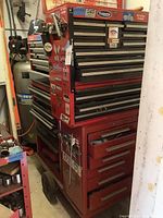 Overview of stacked red tool chests on wheeled cart in storage area